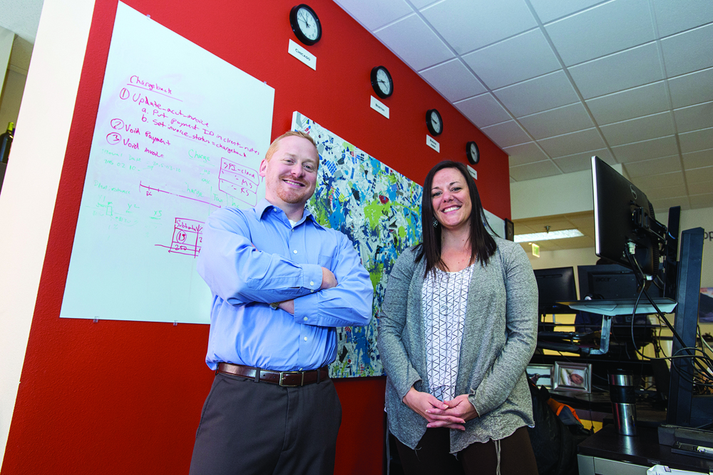 Working at ATG gave Jason Anderson ’09, left, the opportunity to return to Missoula from a job in Portland, Ore. Kristin Mickey ’14, started working at ATG as a student at UM and recently was promoted to knowledge management coordinator.